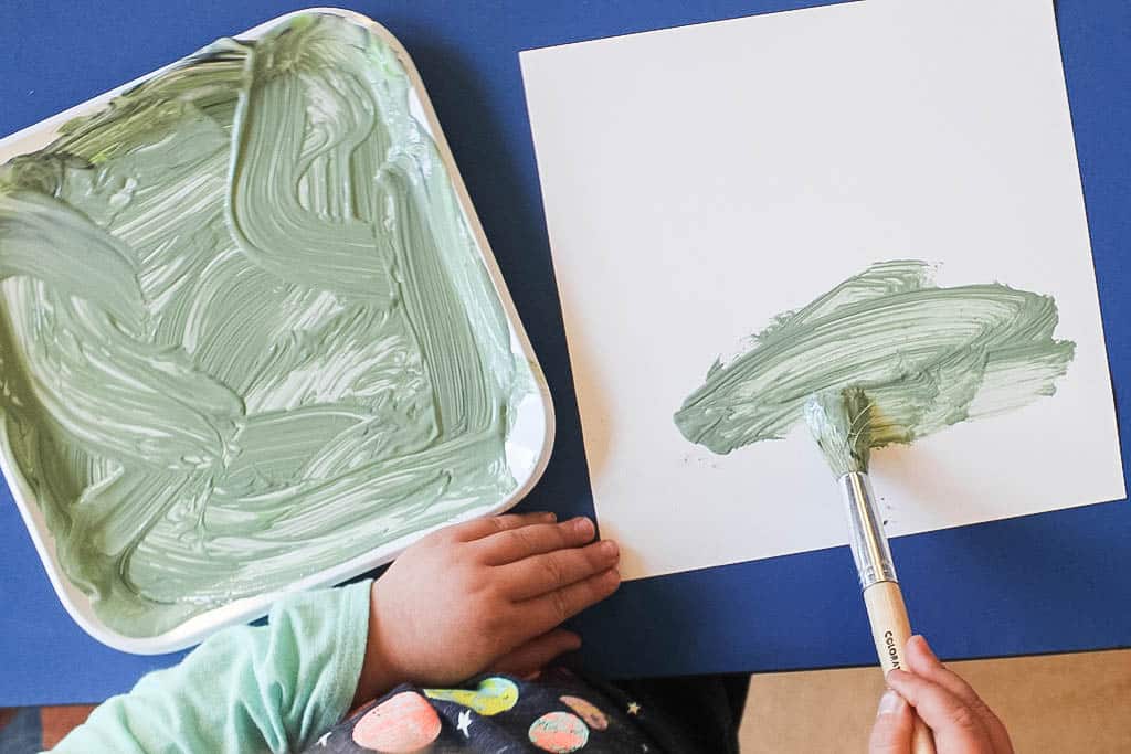 close up of kid's hands painting on paper